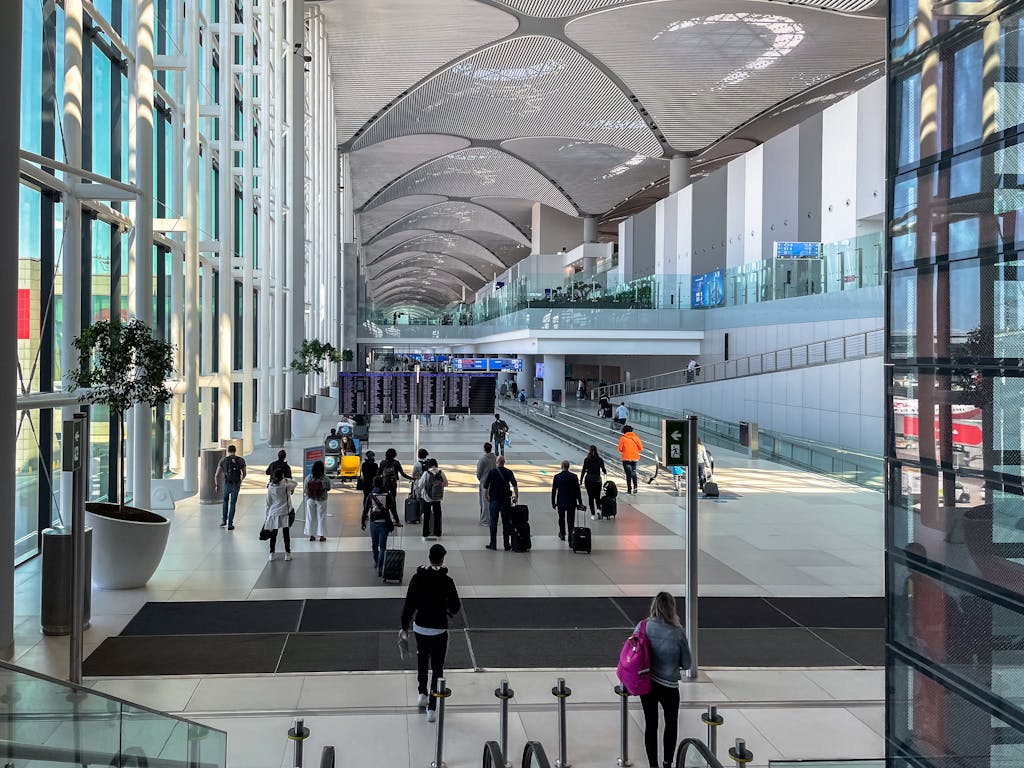 Travelers walking through the spacious modern terminal at Istanbul Airport.